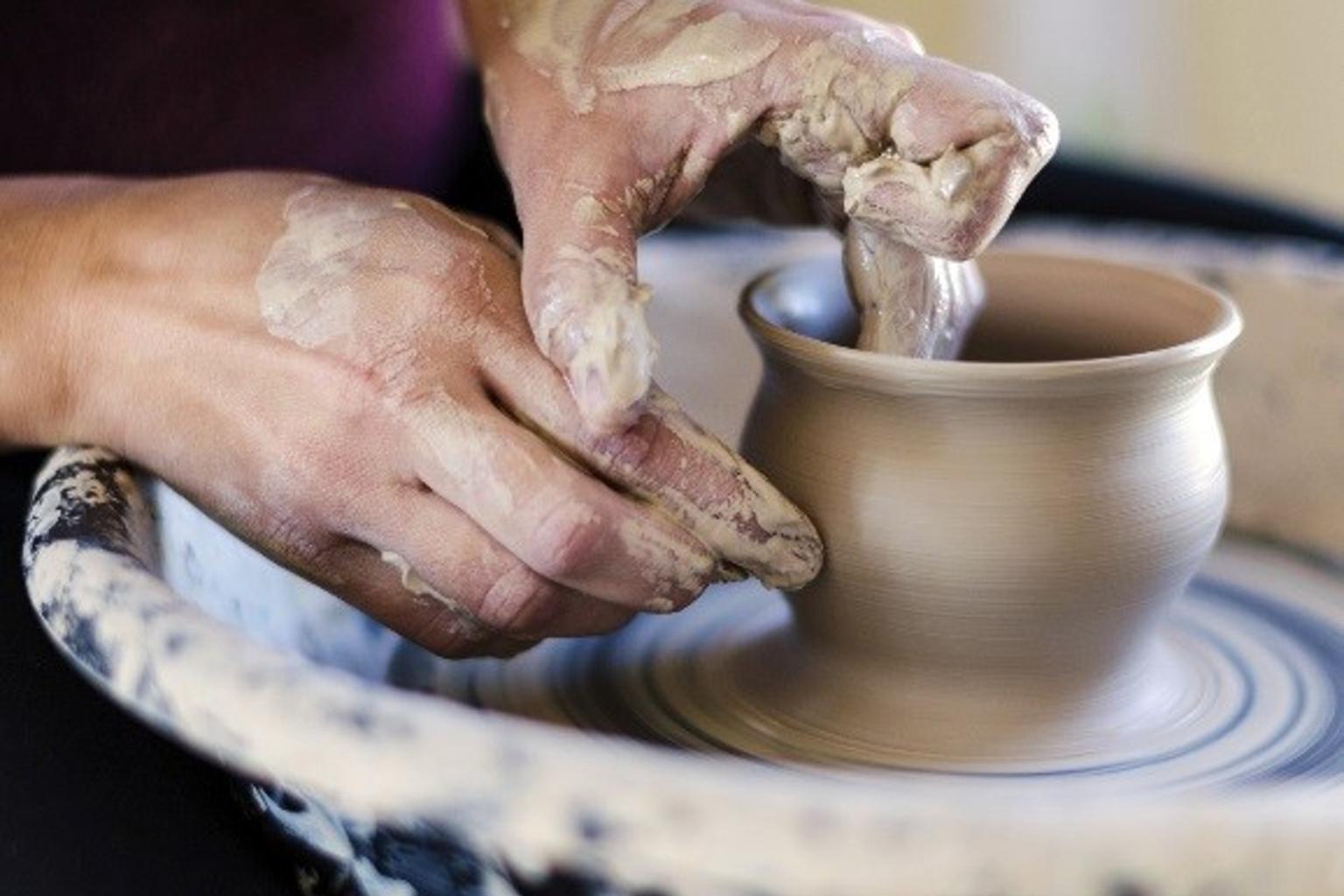 A person making a clay pot with their hands.